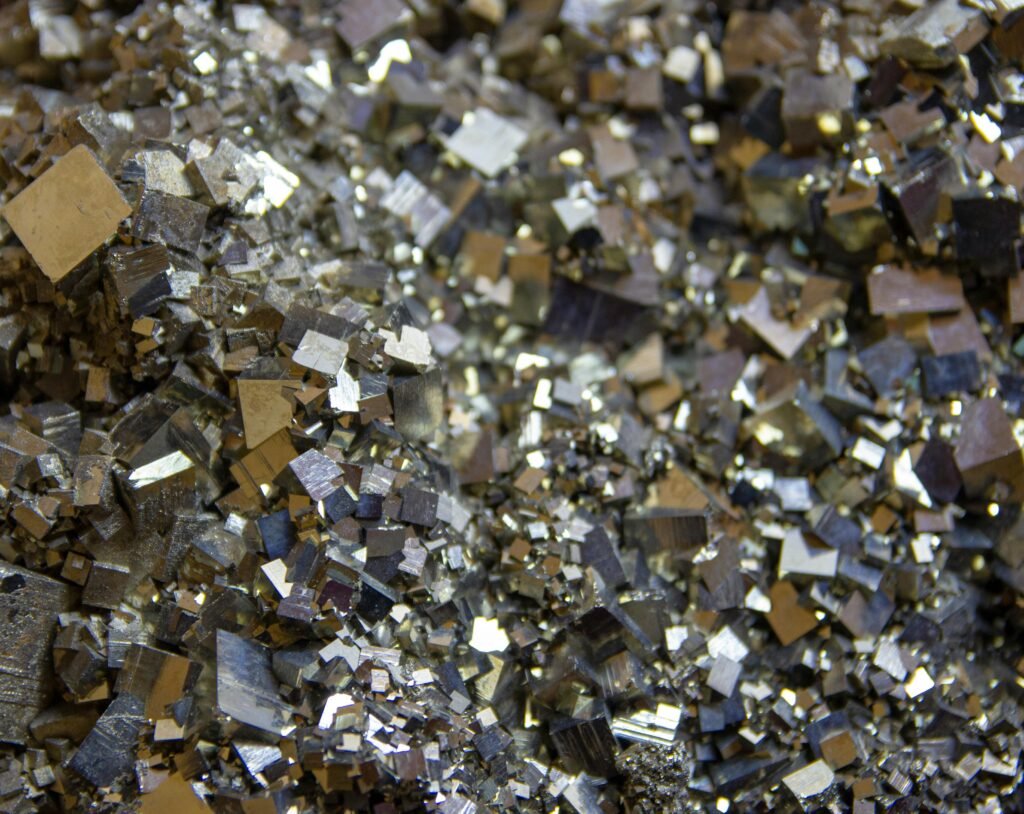 pexels-photo-12275694-12275694 Detailed view of shiny pyrite crystals showcasing intricate metallic textures and patterns.